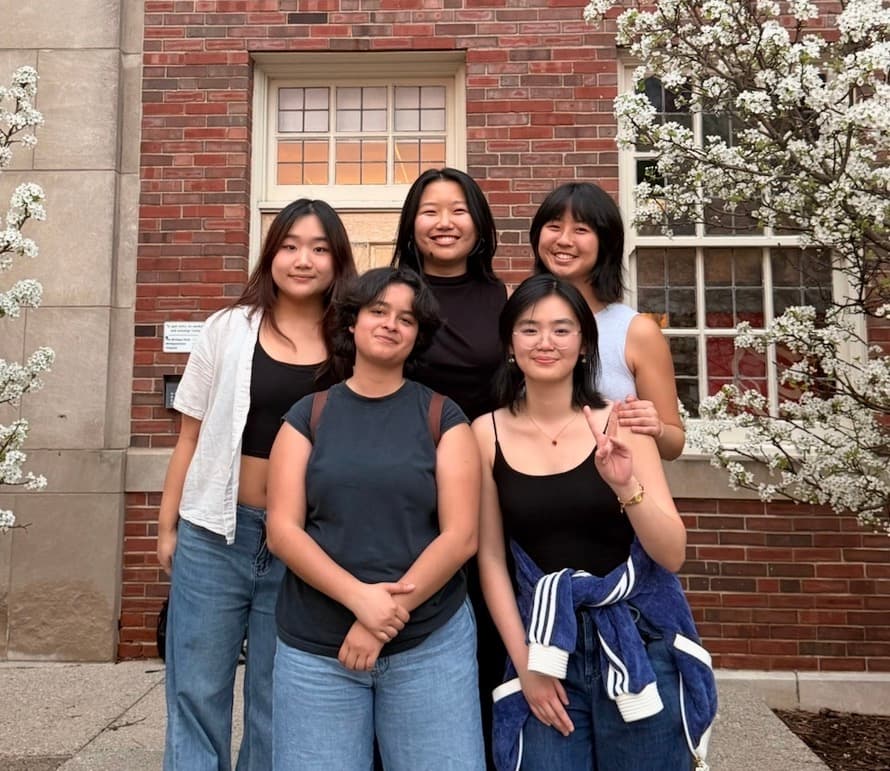 Picture of the 5 band members of Playing Koi, standing outside of a brick building