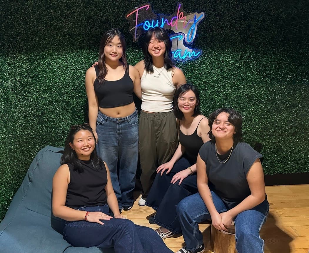 5 members of Playing Koi sitting in front of a wall of synthetic leaves
